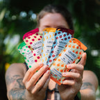 Person holding multiple Lecka energy gel packets with a blurred green background