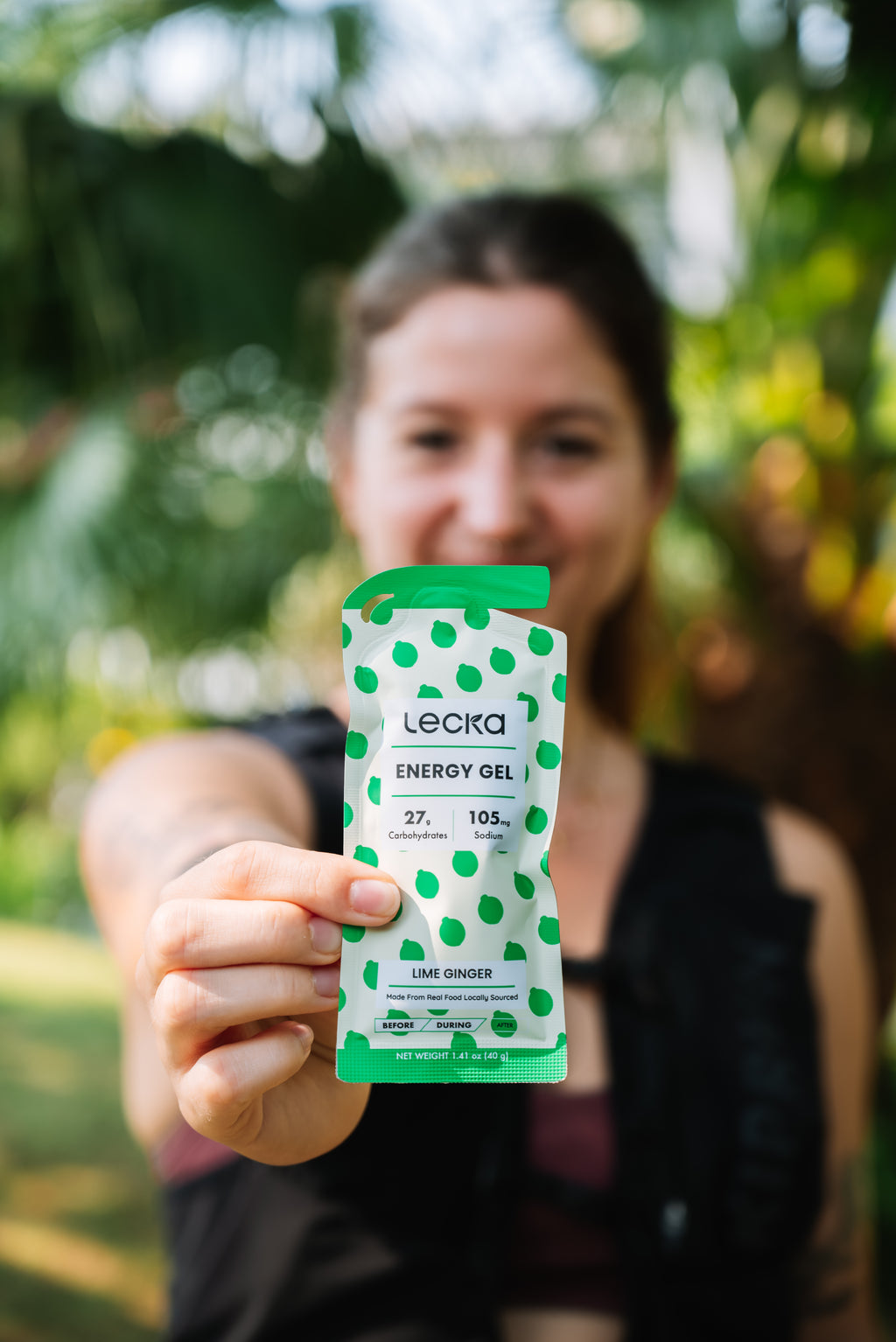 Person holding a Leela energy gel package outdoors with greenery in the background