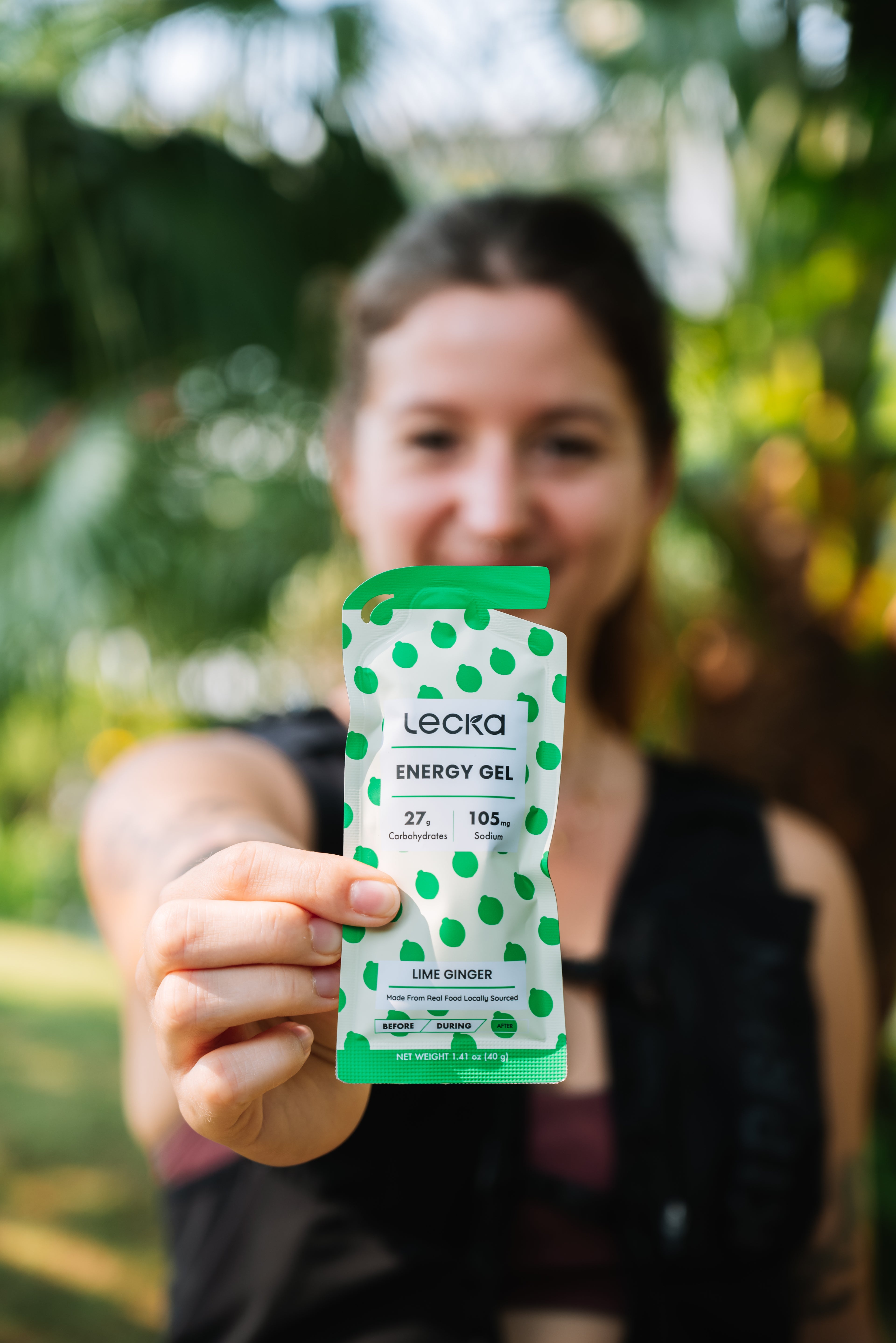 Person holding a Leela energy gel package outdoors with greenery in the background